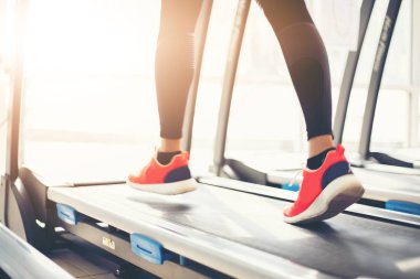 Genç bir beyaz kadın koşu treadmill sahip iken, spor ayakkabı spor salonunda çalışan bulanık