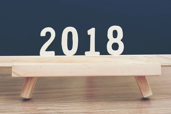 wood word of 2018 numbers lie on wooden table and black background. Empty copy space for merry christmas and new year 2018 holiday