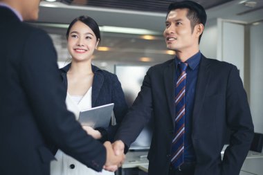 El sıkışan ve sözleşme ve bir buluşma bitirme imzalamak için onların anlaşma gülümseyen iş adamları