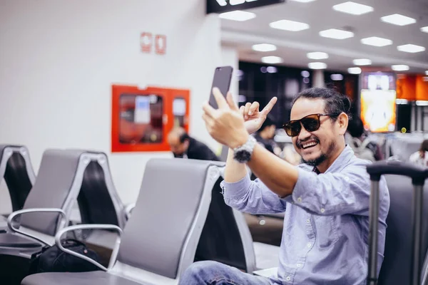 亚洲男子背包旅客使用智能手机视频通话和采取在机场 — 图库照片