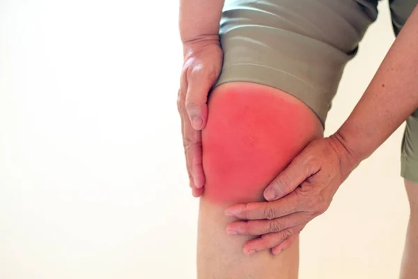 Enfoque suave de las mujeres asiáticas de edad a la lesión de rodilla sobre fondo blanco — Foto de Stock