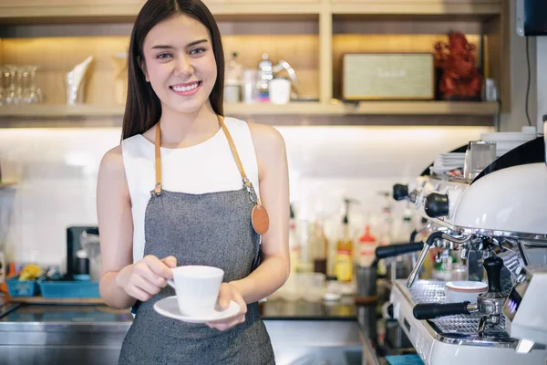 Азіатські жінки Barista посміхається і за допомогою кавомашину в s кави — стокове фото