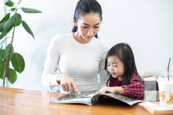 Mom is teaching her daughter to read a book