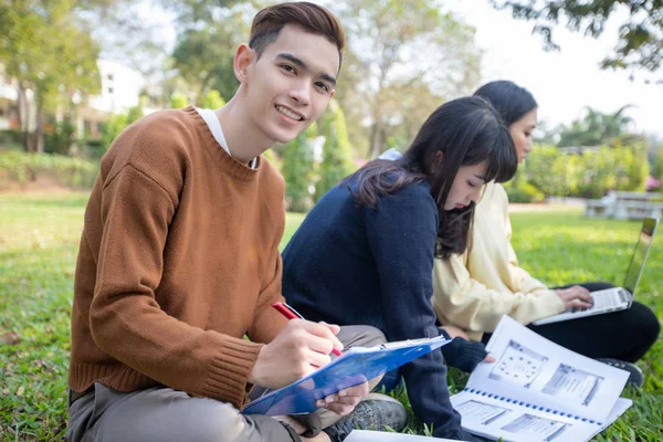 Grupo de universidad estudiantes asiático sentado en el verde hierba w — Foto de Stock