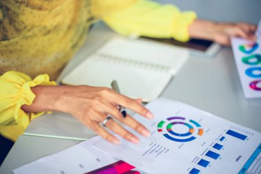 Müslüman iş kadınları ofis masasında belgeleri analiz ve arka planda çalışan grafik mali diyagram var