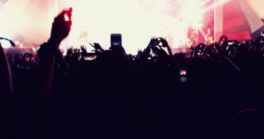 Arka görünümü parlak sahne ışıkları ellerini yükselterek festival kalabalık konser kalabalığa siluetleri, bulanık