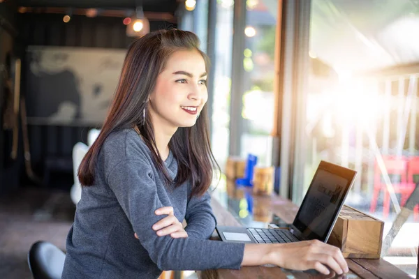Kafede uzaktan çalışan dizüstü bilgisayar kullanan neşeli sian iş kadını.