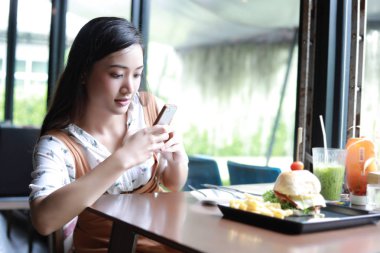 Asyalı kadınlar hamburger fotoğraf çekmek ve dinlenmek zaman kahve ve restoranda yemek zevk