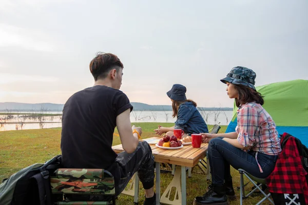 A group of Asian friends drinking coffee and spending time making a picnic in the summer holidays.They are happy and have fun on holidays.