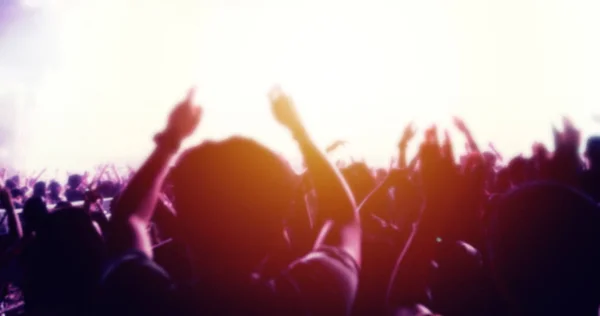 明るい舞台照明に手を上げてお祭りの群衆の後姿でコンサートの群集のシルエット ロイヤリティフリーのストック写真