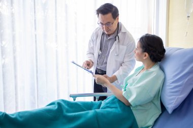 doktor hastanede yatakta yatan kadın hastaya beyin röntgensonuçları hakkında açıklama
