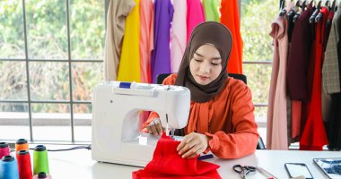 Müslüman kadın moda tasarımcısının çalıştığı, akıllı telefon ve tablet kullandığı küçük bir işletme.