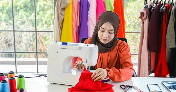 Müslüman kadın moda tasarımcısının çalıştığı, akıllı telefon ve tablet kullandığı küçük bir işletme.