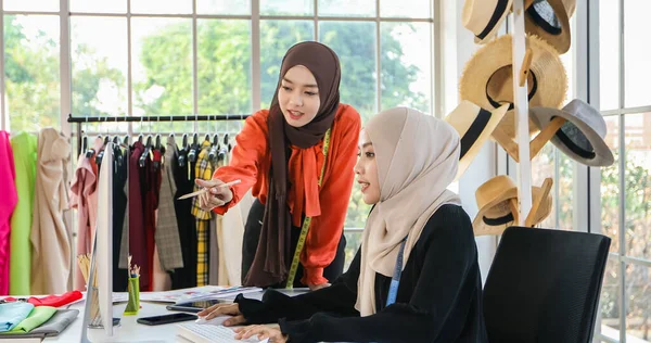 Müslüman kadın moda tasarımcısının çalıştığı, akıllı telefon ve tablet kullandığı küçük bir işletme.