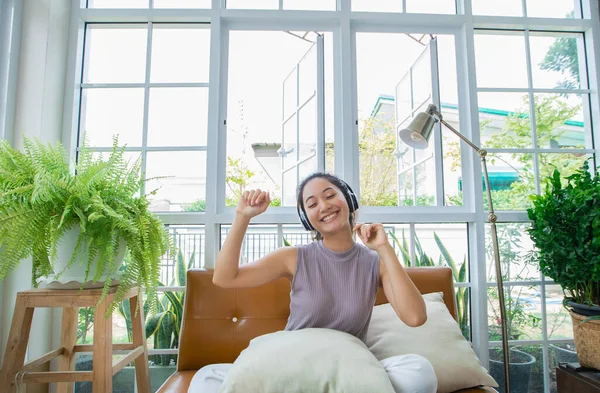 Asian women wearing headphones and using laptop and digital tablet for Listening to music and singing on a relaxing day at home