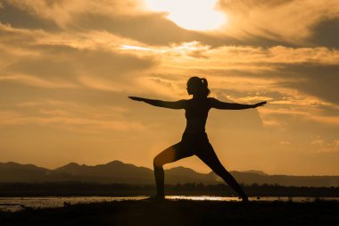 Siluet Asyalı kadınlar akşam nehir kenarında yoga yaparak egzersiz yapıyorlar.. 