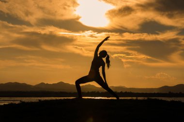 Siluet Asyalı kadınlar akşam nehir kenarında yoga yaparak egzersiz yapıyorlar.. 