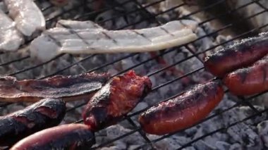 Chorizo cocinandose sobre una parrilla con fuego debajo para una barbacoa. Izgarada Chorizo pişiyor, altında barbekü ateşi var..