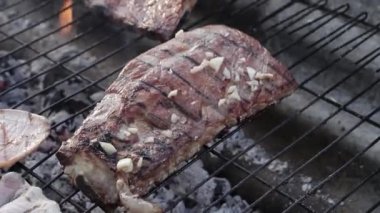 Costillas de cerdo con ajo por encima sobre una parrilla en una barbacoa. Izgaranın üstünde sarımsaklı domuz pirzolası.