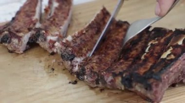 Una mano de un chico con un cuchillo cortando costillas sobre una tabla de mader. ahşap bir tahtada kaburga kesen bir çocuğun eli..