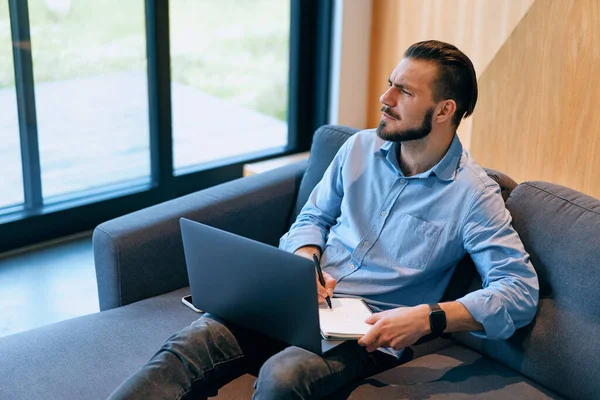 Side view of exhausted business man searching for solution using laptop