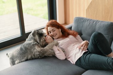 Köpeğiyle oynayan güzel genç bir kadının portresi.