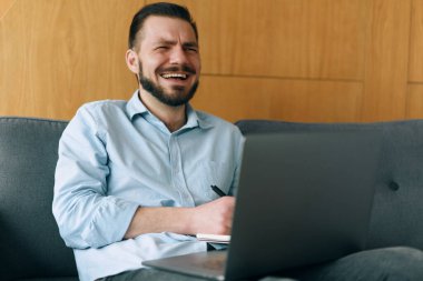 Laptop kullanan, klavyede yazan ve gülen yakışıklı bir adam.