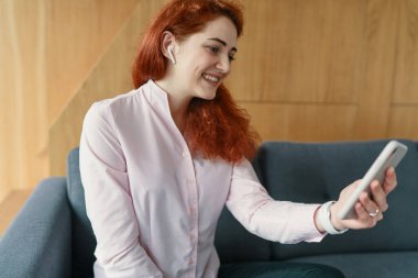 Genç iş kadını evde akıllı telefonuyla video görüşmesi yapıyor.