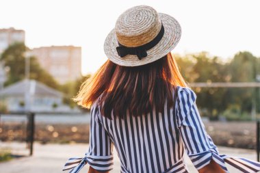 arkadan çizgili elbise ve hasır şapka giyen genç çekici kadın görünüşü 