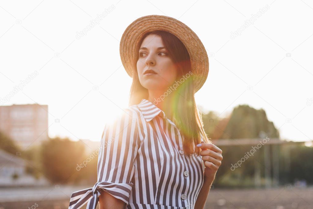 serious young attractive woman wearing striped dress and straw hat 