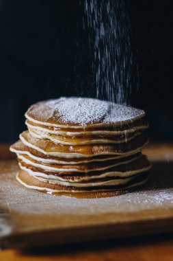Pudra şekeri ile krep yığını üzerinde ahşap masa su sıçramalarına
