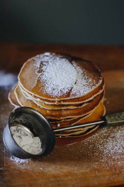 Ahşap tahta üzerinde bal ve şeker tozu ile krep yığını