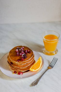 Kızılcık ve akçaağaç şurubu ve mermer zemin üzerine portakal suyu ile krep yığını