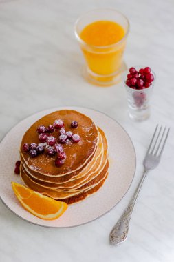 Kızılcık ve akçaağaç şurubu ve mermer zemin üzerine portakal suyu ile krep yığını