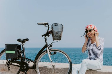 Güzel genç kadın bir plajda müzik dinlemek bisiklet ile