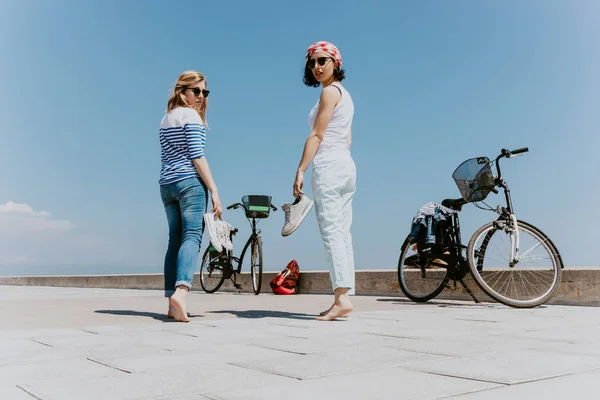 Twee Jonge Vrouwen Die Met Plezier Het Strand Met Fietsen — Stockfoto