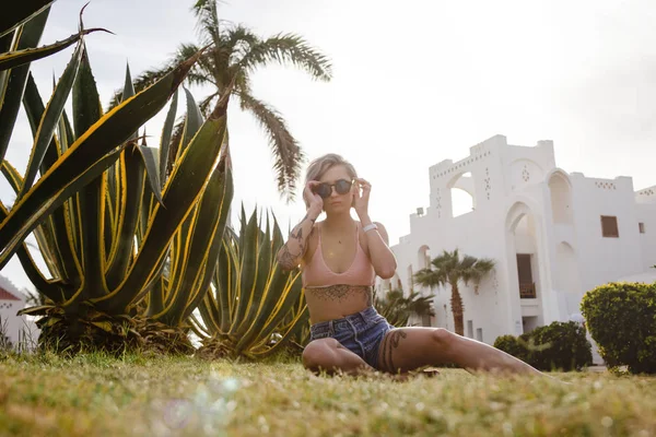 Sexig ung kvinna som sitter på grönt gräs njuter av solen — Stockfoto