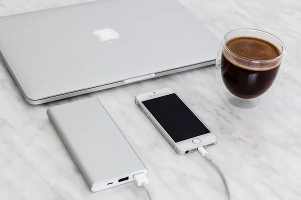 IPhone SE зарядки з потужністю банк, MacBook і чашка кави на тлі мармуру — стокове фото