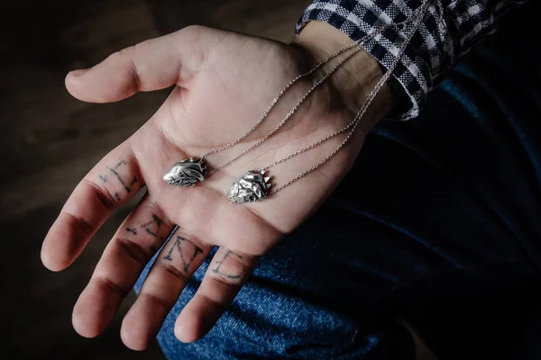 Man hand holding silver heart shape pendants — Stock Photo, Image