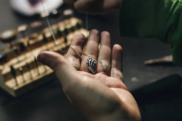 Close up de mão de joalheiro com pingente de forma de coração — Fotografia de Stock