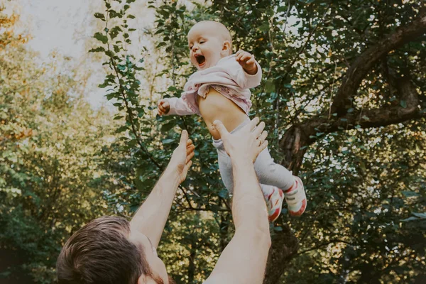 Padre arrojando a su pequeña hija al aire en el bosque — Foto de Stock