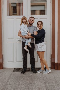 Beyaz kapının yanında küçük kız ile aile