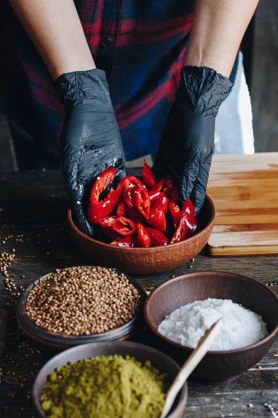 Donna mani in guanti neri mescolando peperoncino rosso piccante — Foto Stock