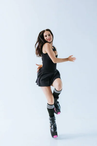 Beautiful fit caucasian woman jumps in shoes for kangoo jumping on white background