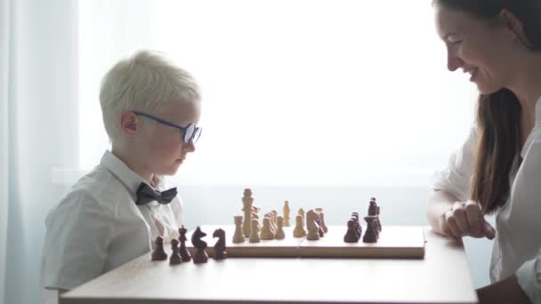 Mãe e filho jogam xadrez na mesa na sala — Vídeo de Stock