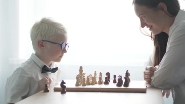 チェスの彼の母と遊ぶ若いアルビノ — ストック動画