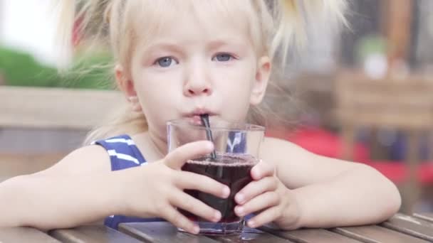 La niña está bebiendo jugo en un café. — Vídeo de stock