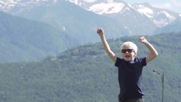 Un chico rubio de vacaciones en las montañas — Vídeos de Stock