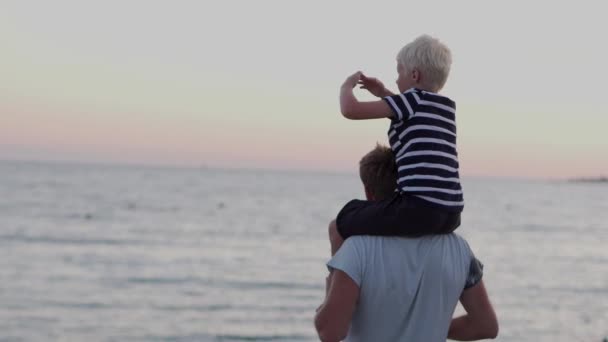 O pai está a ver com o filho ao pôr do sol. — Vídeo de Stock