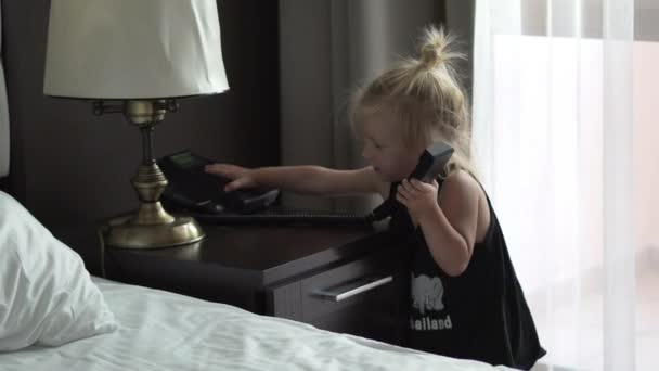 La niña está hablando en la habitación del hotel por teléfono — Vídeos de Stock